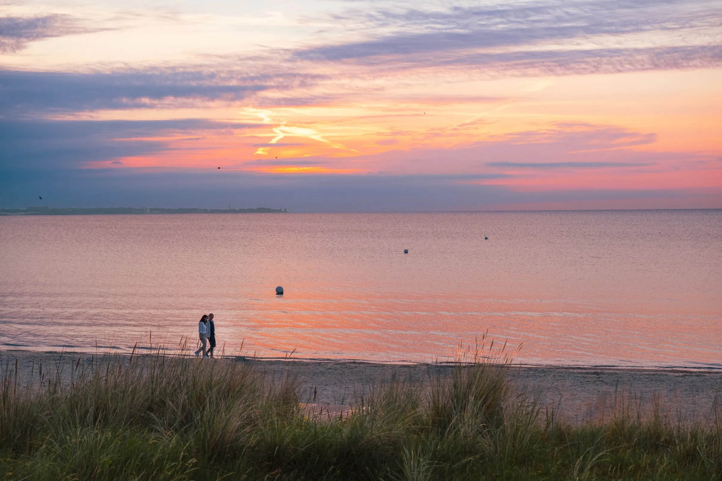 Warmes Abendlicht über der Ostsee bei Scharbeutz – Menschen spazieren am Strand